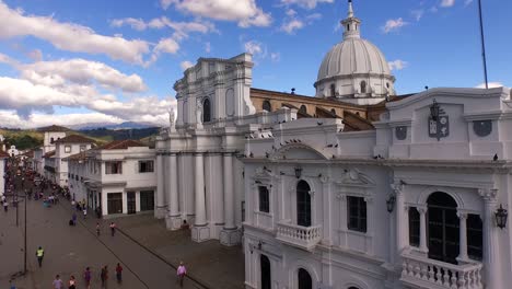 Aerial-shot-rising-diagonally-from-busy-street-to-church-basilica-and-view-of-Popayan,-Colombia