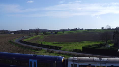 Aerial-rising-shot-of-a-South-eastern-commuter-train-in-the-countryside-near-Ashford,-Kent