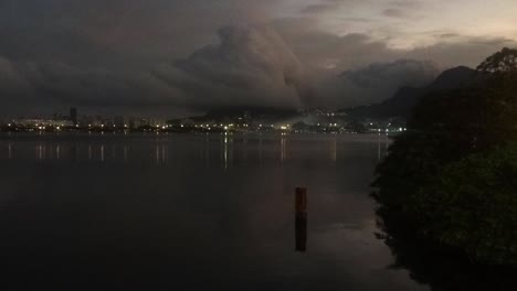 Zeitraffer-Eines-Außergewöhnlichen-Wetterphänomens-Einer-Röhrenförmigen-Wolke,-Die-Vom-Meer-Hereinrollt-Und-Auf-Die-Küstenberge-In-Rio-De-Janeiro-Trifft,-Vom-Stadtsee-Aus-Gesehen