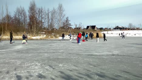 People-enjoy-the-winter,-morning-frost-on-the-frozen-city-pond,-skating-and-walking-on-the-ice