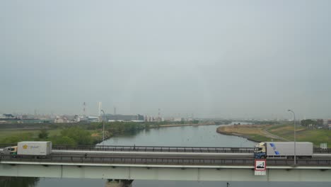 Querformatansicht-Der-Stadt-Tokio-Aus-Dem-Inneren-Des-Fahrenden-Shinkansen-Zuges-Bei-Bewölktem-Himmel-Beim-Überqueren-Des-Flusses