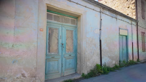 A-worn-blue-door-and-window-on-a-weathered-building-facade-in-Lefkara,-Cyprus