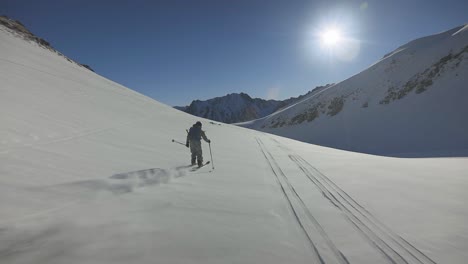 Freeride-Skifahrer-Abseits-Der-Piste,-Skifahren-Im-Frischen,-Tiefen-Pulverschnee-In-Richtung-Sonne-Mit-Einem-Erstaunlichen-Blauen-Himmel-Und-Blick-Auf-Die-Berge