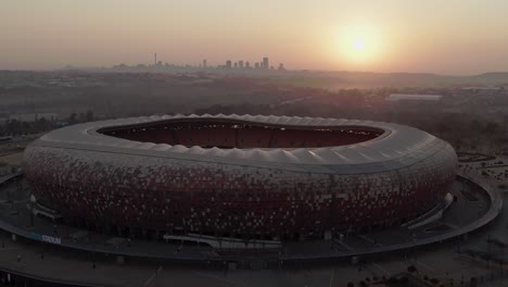 Fnb-Stadium-4k-Drone-Aéreo-Empujando-Posada-Al-Amanecer-Con-Johannesburgo-Cbd-En-La-Distancia_03