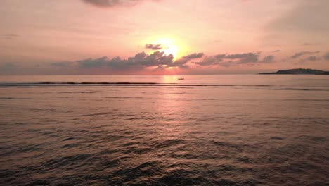 Luftdrohne-Fliegt-Tief-über-Dem-Meer-In-Richtung-Sonne-Bei-Hellem,-Bewölktem-Sonnenuntergang-Auf-Der-Tropischen-Insel-Bali