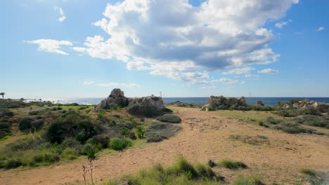 Una-Amplia-Vista-Del-Paisaje-Costero-En-Las-Tumbas-De-Los-Reyes-En-Pafos,-Chipre,-Con-Rocas-Dispersas-Y-Vegetación.