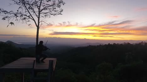 Silhouette-Eines-Mannes,-Der-Bei-Einem-Epischen-Sonnenaufgang-Im-Dorf-Batu-Dulang-Auf-Sumbawa-Geige-Spielt