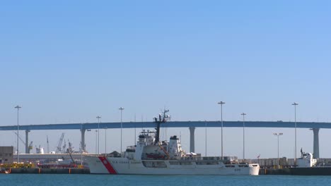 US-Coastguard-Alert-WMEC-630-medium-endurance-cutter-ship-at-the-port-with-Coronado-bridge-in-the-background,-Pan-down-reveal-establishing-shot