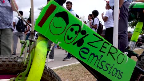 People-gathering,-marching-and-100%-zero-emissions-sign-on-bicycle