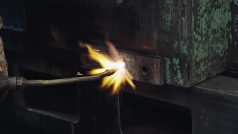 Nahaufnahme-Eines-Arbeiters,-Der-In-Einer-Industriewerkstatt-Maschinen-Schweißt-Und-Dabei-Mit-Einem-Lötkolben-Intensive-Flammen-Erzeugt