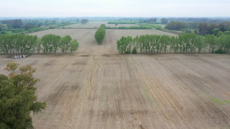 Aerial-view-of-agricultural-landscape-empty-fields-soil-in-preparation-for-sowing-black-soy-seeds-and-planting-wheat,-Drone-camera-slowly-moving-backwards