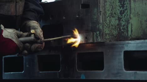 Nahaufnahme-Eines-Arbeiters,-Der-In-Einer-Industriewerkstatt-Mit-Einem-Lötkolben-Maschinen-Schweißt,-Wobei-Das-Metall-Durch-Flammen-Erhitzt-Wird