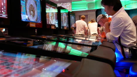 Bewegung-Von-Menschen,-Die-Casino-Roulette-An-Einem-Automaten-Spielen,-Mit-Spiegelung-Einer-Sich-Drehenden-Kugel-Auf-Dem-Bildschirm-Im-Casino