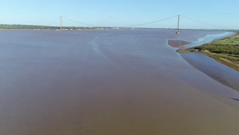 A-reverse-aerial-view-of-the-River-Humber-in-the-UK-showing-the-mudflats-and-the-iconic-Humber-Bridge-in-the-background