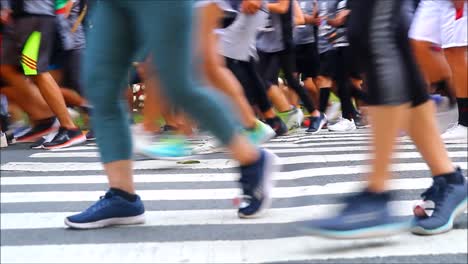 QUEZON-CITY,-PHILIPPINES-–-JULY-9,-2019:-Handheld-low-angle-video-shot-of-people-running-across-a-pedestrian-lane-during-a-marathon-race