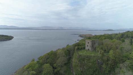 Aerial-shot-over-Dunollie-castle,-Oban,-headed-North-West-over-the-trees-out-to-sea