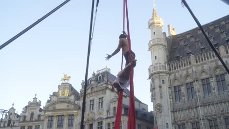 Young-Street-Performers-Couple-giving-an-exciting-show-at-the-Grand-Place-of-Brussels,-Belgium,-in-front-of-a-crowd-on-a-warm-summer-evening-during-sunset