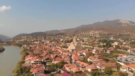 Aerial-view-of-the-Svetitskhoveli-Cathedral-in-the-city-of-Mtskheta,-Georgia,-and-the-main-river-of-the-city
