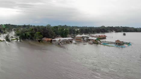 4K-Luftaufnahmen,-Die-Rückwärts-Fliegen,-Zeigen-Die-Aufnahme-Einer-Schule-Auf-Der-Majuli-Flussinsel,-Die-Von-Den-Überschwemmungen-Des-Brahmaputra-Monsuns-überschwemmt-Ist