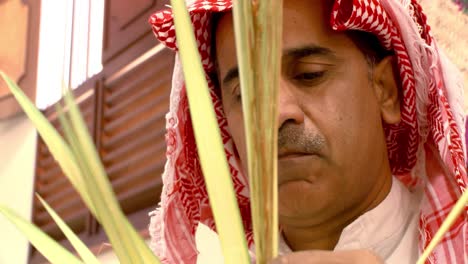 A-Bahraini-man-dressed-in-traditional-Arabian-clothes-weaving-baskets-from-palm-fronds-in-the-village-of-Bani-Jamra-in-Bahrain