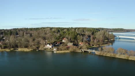 Peaceful-charming-Swedish-settlement-Ekolsund,-Sweden-in-harmony-with-nature-on-the-banks-of-the-river-with-highway-bridges-in-the-background