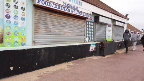 Over-weight-People-walk-in-front-closed-run-down-takeaway-shop