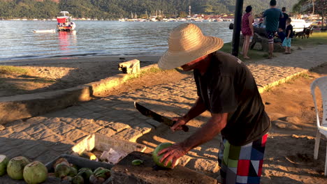 Brasilianischer-Mann-Schnitzt-Melone,-Im-Hintergrund-Ist-Der-Kleine-Hafen-Zu-Sehen