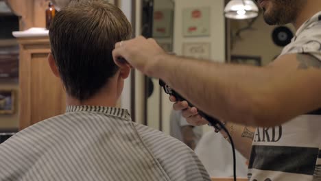 Young-Adult-Male-Having-Haircut-In-Barbershop,-rear-view