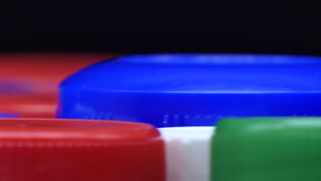 Upper-part-of-colored-plastic-caps-that-rotate,-very-low-depth-of-field,-Closeup-front-view