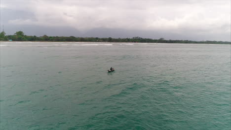 AERIAL:-Slow-motion-Honduran-fisherman-fishing-from-canoe-in-open-ocean---El-Porvenir,-Honduras