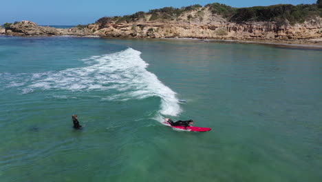 Aerial:-Two-young-surf-students-catch-the-same-small-shore-break-wave