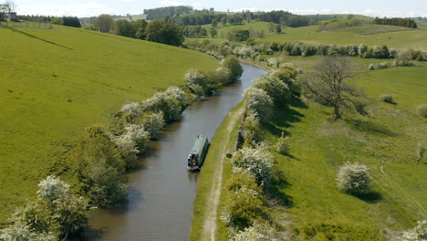 An-aerial-view-of-a-canal-and-canal-boat-surrounded-by-Yorkshire-countryside-on-a-sunny-spring-day