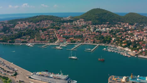 Aerial-pan-shot-following-sailing-boats,-cruise-ships-and-ferry-boats-in-Dubrovnik-port