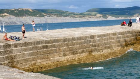 A-teenager-jumps-or-dives-off-of-a-pier-into-the-ocean