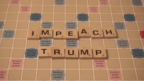 The-words-"Impeach-Trump"-spelled-out-in-wooden-letters-on-Scrabble-game-board