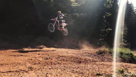 Two-racers-on-motocross-bikes-jumping-over-a-big-jump-on-track-in-slow-motion