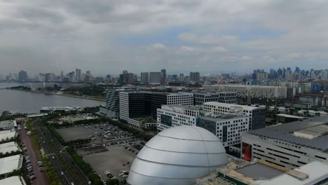 A-shot-of-the-Metro-Manila-skyline,-moving-down-to-reveal-the-MoA-IMAX-cinema-complex