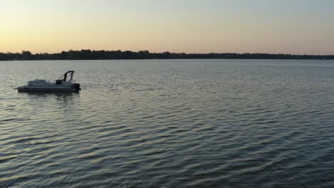 Forward-moving-drone-shot-of-a-lake-at-sunrise-from-the-dock,-passing-by-a-person-with-a-camera