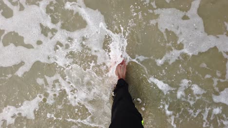 Feet-of-man-walking-barefoot-on-shore-in-slow-motion