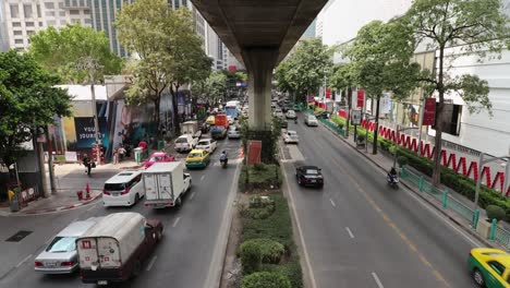 Zeitrafferaufnahme-über-Einer-Viel-Befahrenen-Straße-In-Bangkok-Aus-Großer-Höhe-Mit-Vielen-Vorbeifahrenden-Autos-Und-Taxis