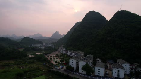 Yangshuo-Al-Amanecer-Con-Montañas-Brumosas-Y-Un-Pequeño-Pueblo-Ubicado-Debajo,-China