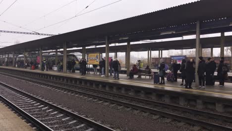 Pendolino-train-arriving-at-Ostrava-Svinov-train-station-with-platform-full-of-people-in-foggy-day,-panning-shot