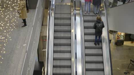 People-traveling-on-escalators-at-train-station-with-Christmas-lights