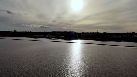 Lettland,-Europa-–-Ein-Ruhiger-Abschnitt-Des-Flusses-Daugava-Unter-Einem-Teilweise-Bewölkten-Himmel-Mit-Dem-Spiegelbild-Der-Sonne,-Das-Auf-Dem-Wasser-Schimmert-–-Eine-Drohne-Fliegt-Vorwärts