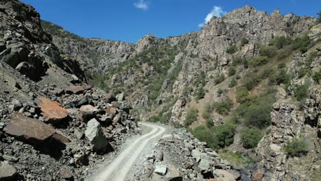 Vías-Aéreas-Bajas,-Estrecho-Camino-De-Grava-En-El-Fondo-De-Un-Desfiladero-De-Roca-Escarpada.