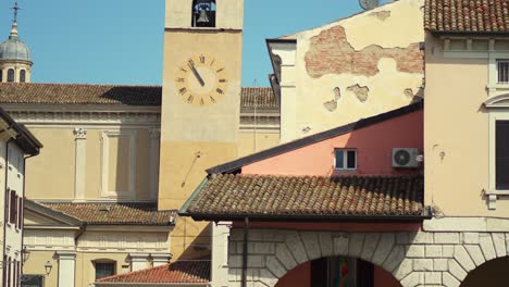 Church-and-tower-bell-of-a-small-town-in-Italy-with-bar-and-cafe-under-the-patios