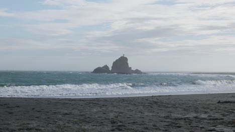 Vista-De-Las-Rocas-Y-El-Faro-Desde-La-Playa-De-Whatipu,-Omanawanui,-Nueva-Zelanda