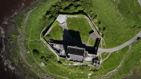 Rotating-aerial-top-down-of-Dunguaire-Castle-showcasing-its-walls-and-walkway-to-the-tower