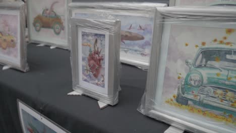 Collection-of-framed-works-of-art,-watercolor-painting-is-displayed-on-the-table