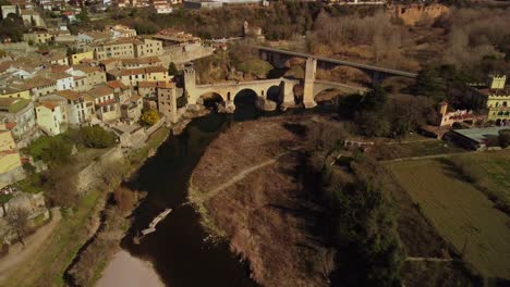 Histórica-Ciudad-De-Besalú-En-Girona,-España,-Con-Un-Antiguo-Puente-De-Piedra-Y-El-Paisaje-Circundante,-Vista-Aérea